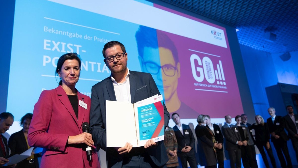Thomas Neumann, responsible at KIT for the topic of start-ups and holdings, received the certificate for KIT; left in picture: Dr. Sabine Hepperle from BMWi. (Photo: Bildkraftwerk)