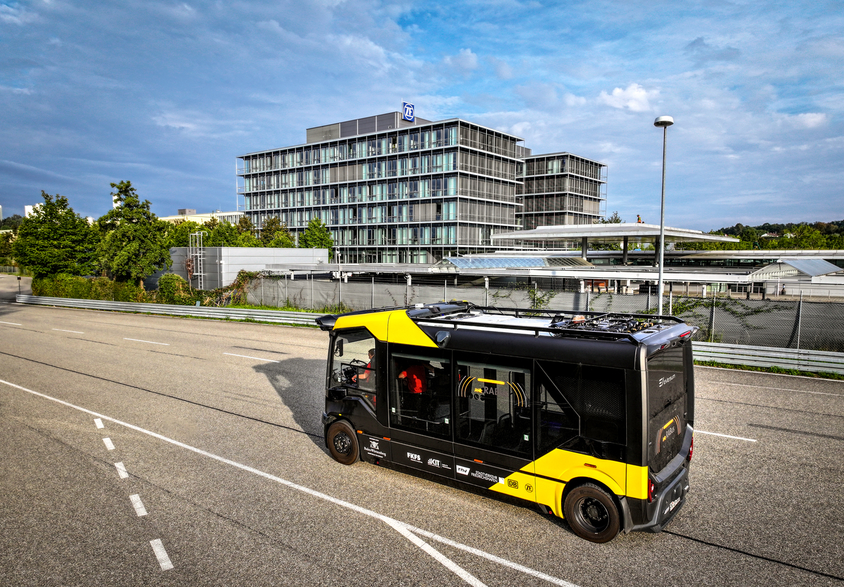Yellow bus driving on the street in fron of a building