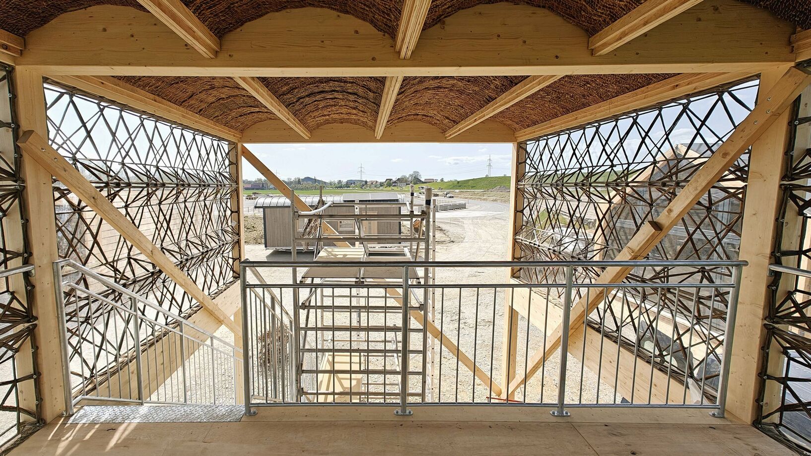 KIT Wooden structure with metal railings and lattice design, overlooking a construction site.
