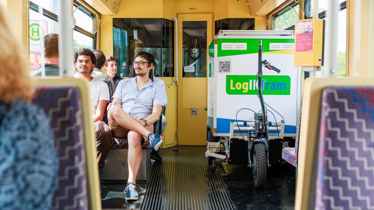AVG People sitting in a tram with a cargo bike labeled "LogIKTram" inside.