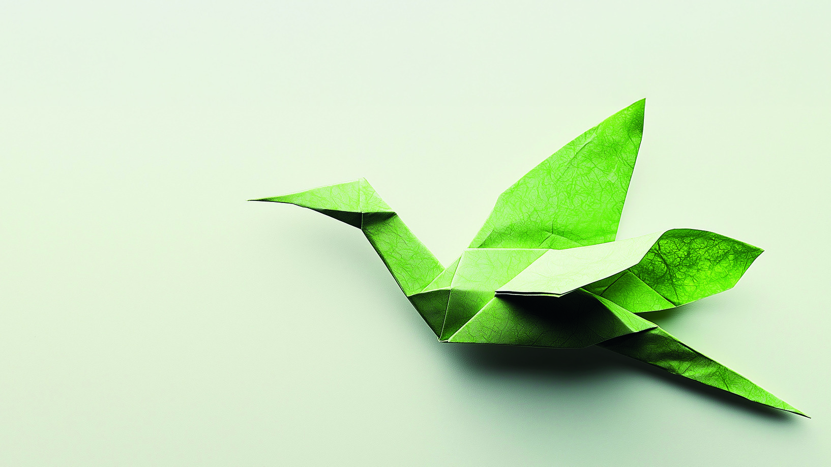 AdobeStock Green origami crane on a light background.