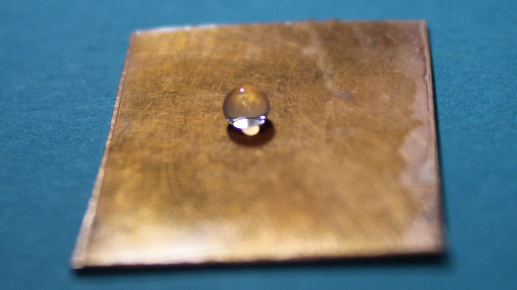 Wassertropfen perlt auf Kupferplatte, die mit dem neuen transparenten Werkstoff Fluororpor beschichtet wurde.