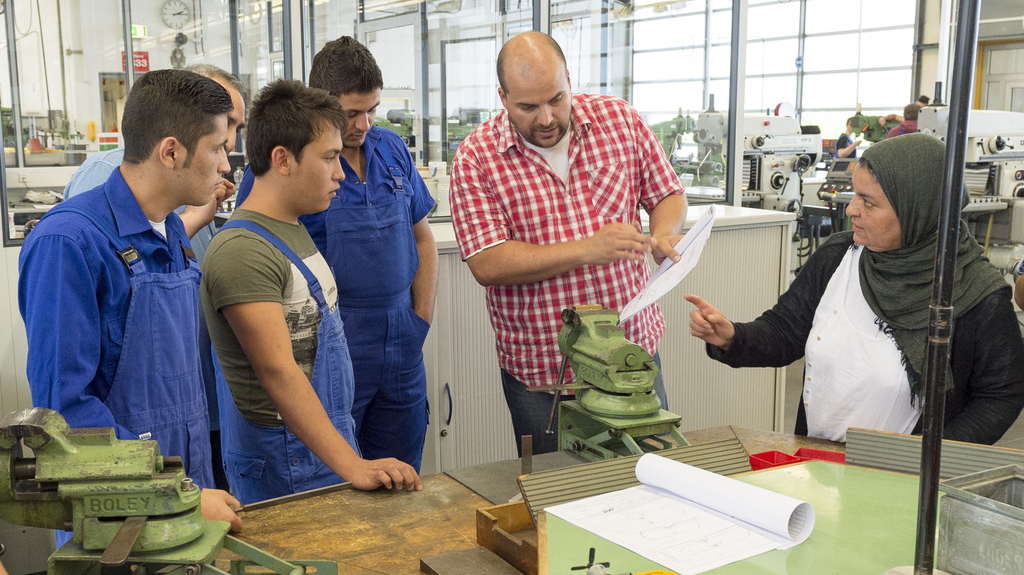 Ausbilder erläutert jungen Flüchtlingen die Arbeit