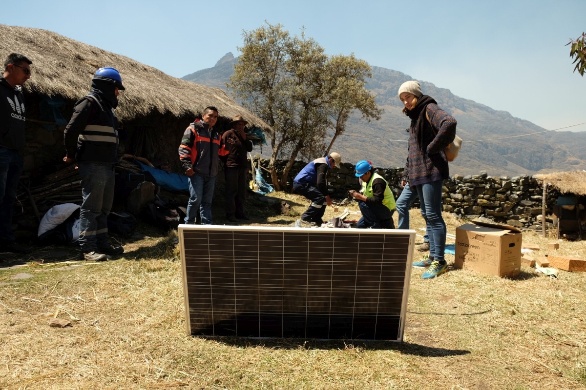 Vor einem Haus bauen Ingenieure ein Solarpanel auf, um für Elektrizität zu sorgen.