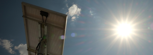 Blick von unten auf ein Solarmodul und in strahlendes Sonnenlicht 