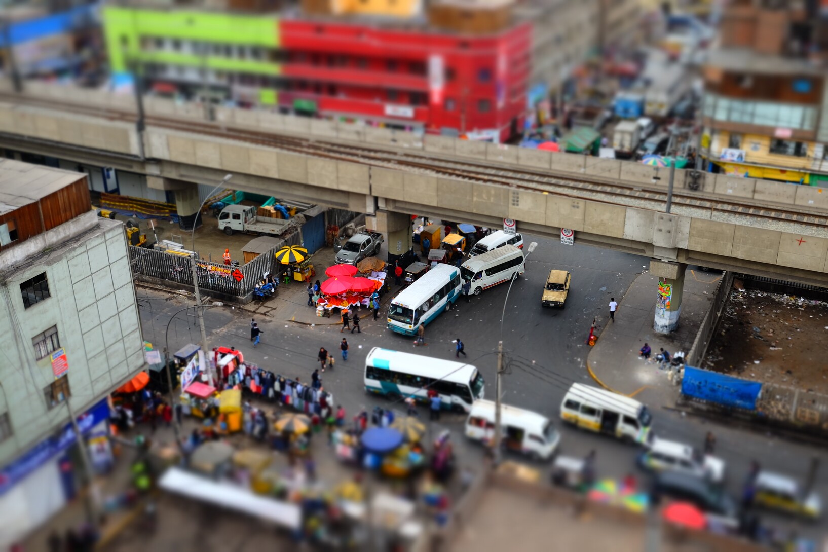 View from above on a street intersection: Queues of cars, market stalls lined up on the sidewalks. 