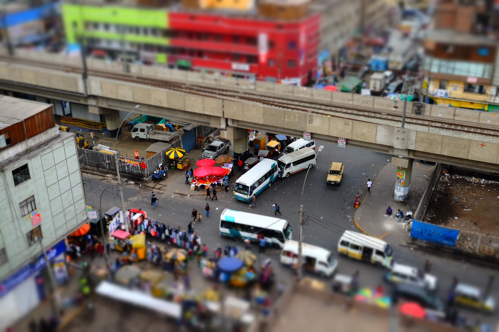 Alena Fernandes de Freitas View from above on a street intersection: Queues of cars, market stalls lined up on the sidewalks.