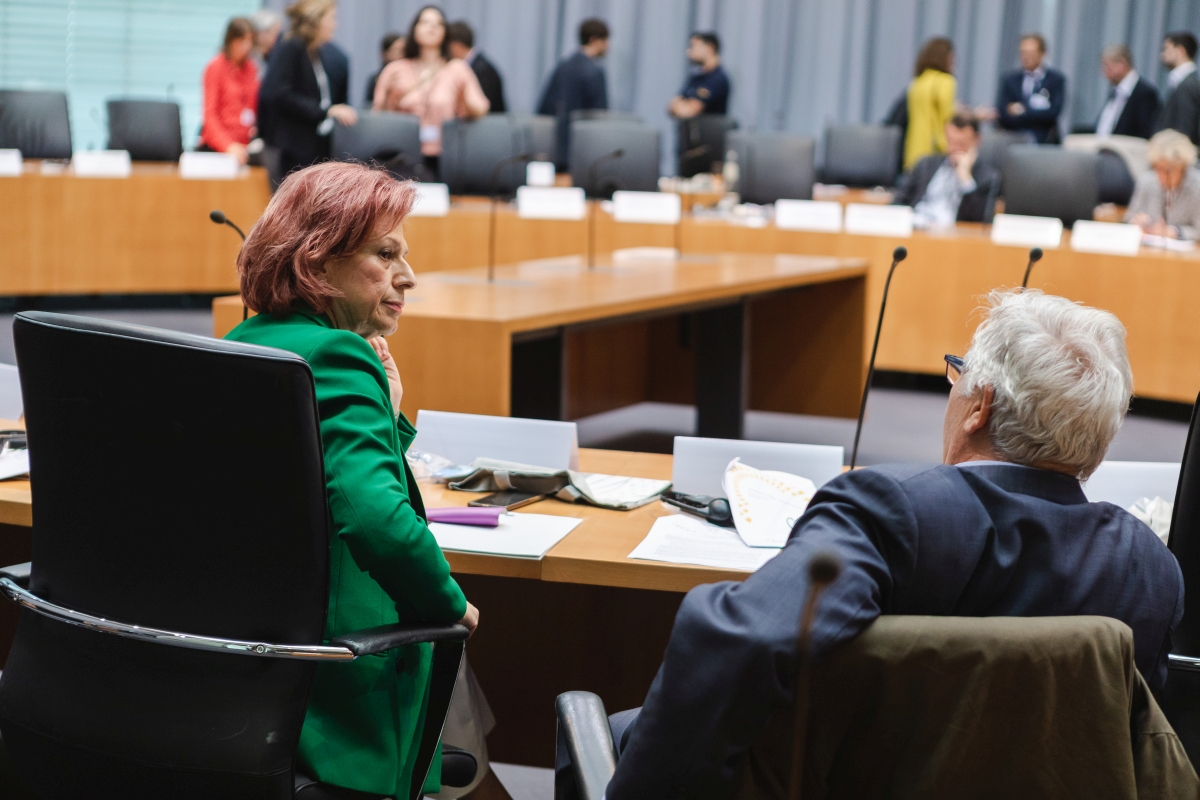 Eine Frau und ein Mann sitzen an ihren Tischen und unterhalten sich angeregt.