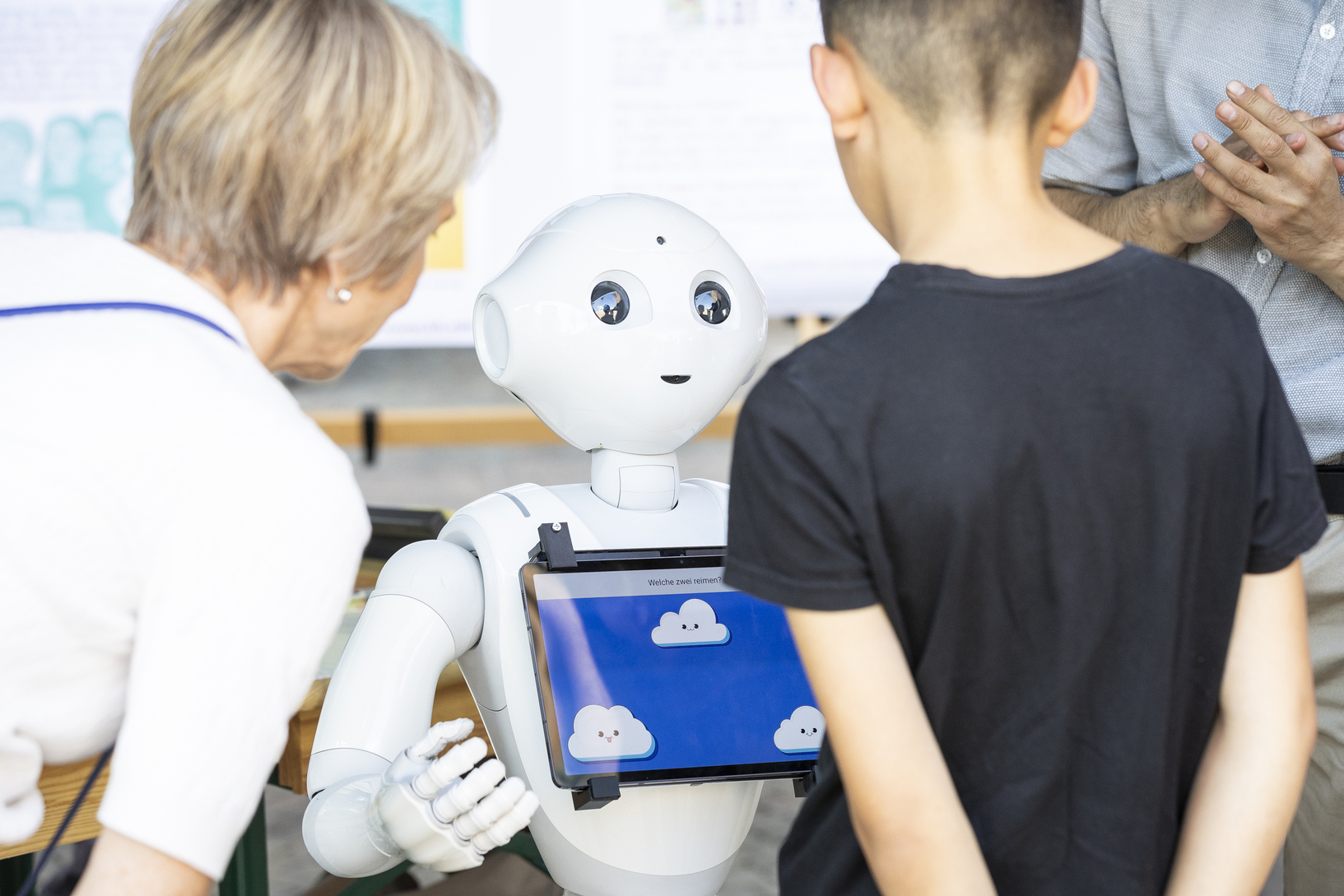  Two spectators standing in front of a humanoid robot holding a tabled