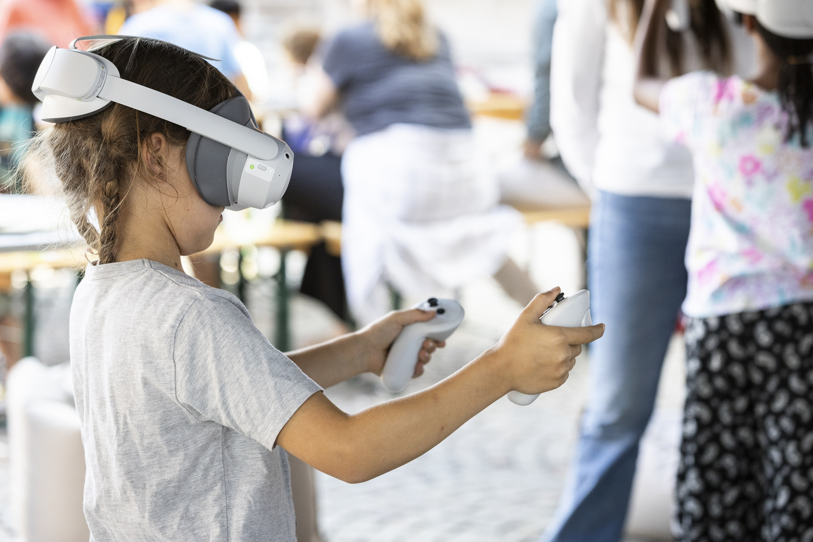  A kid wearing a mixed reality headset and holding a controller in each hand