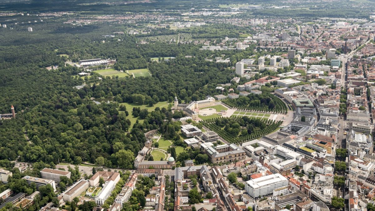 Markus Breig, KIT Aerial view of a city with a large park, featuring geometric gardens and surrounding buildings.