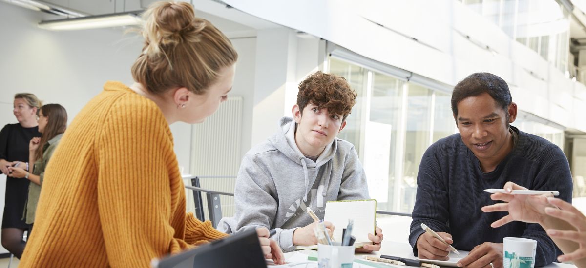 Eine junge Frau berät zwei Studierende des KIT