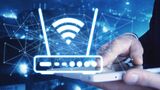 Router und Wlan Zeichen symbolisch dargestellt, eine Hand, die ein handy hält